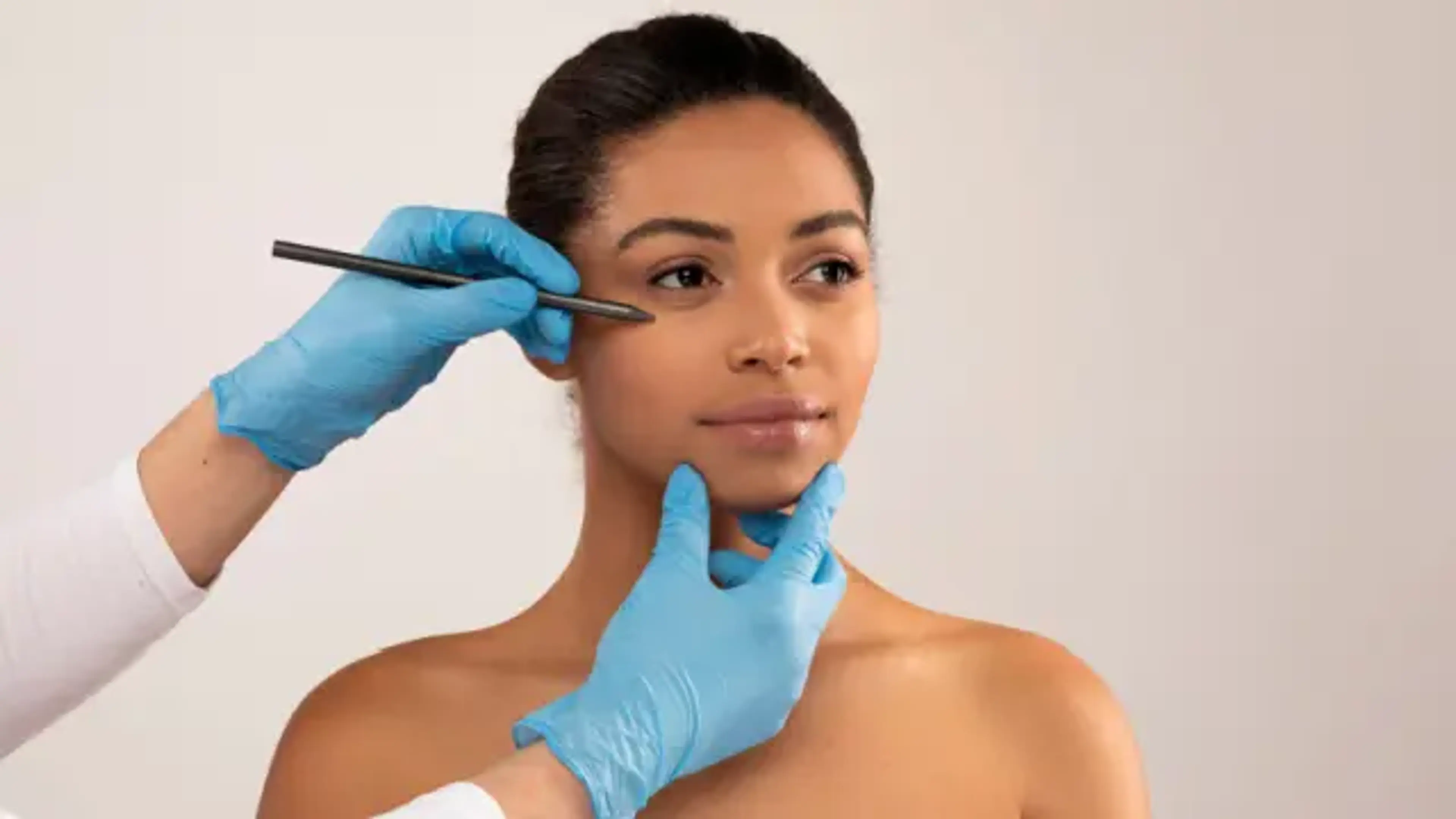 Surgeon marking facial areas for facelift procedure during aesthetic consultation
