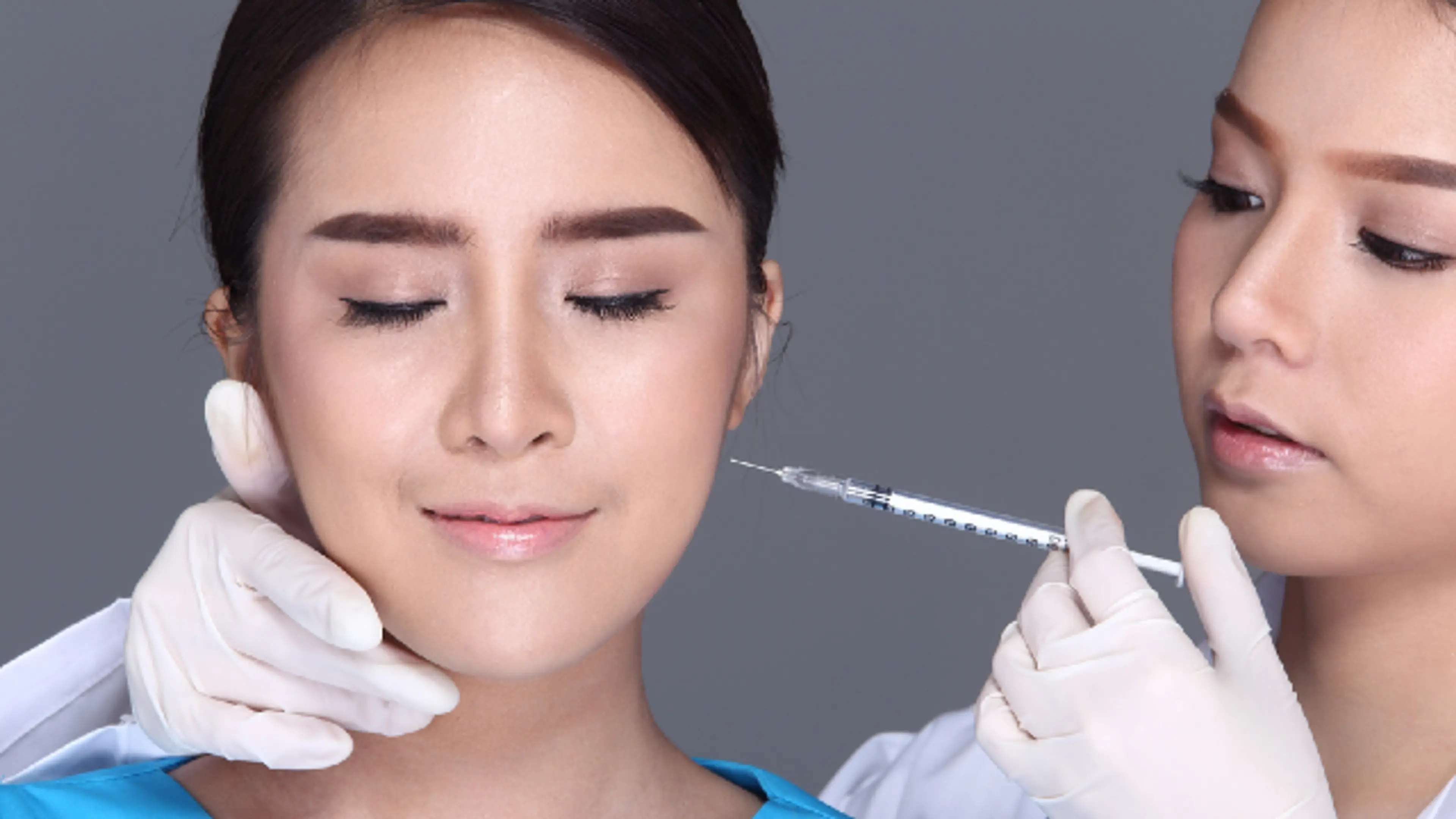 A clinician in white gloves administering a facial injection to a woman.