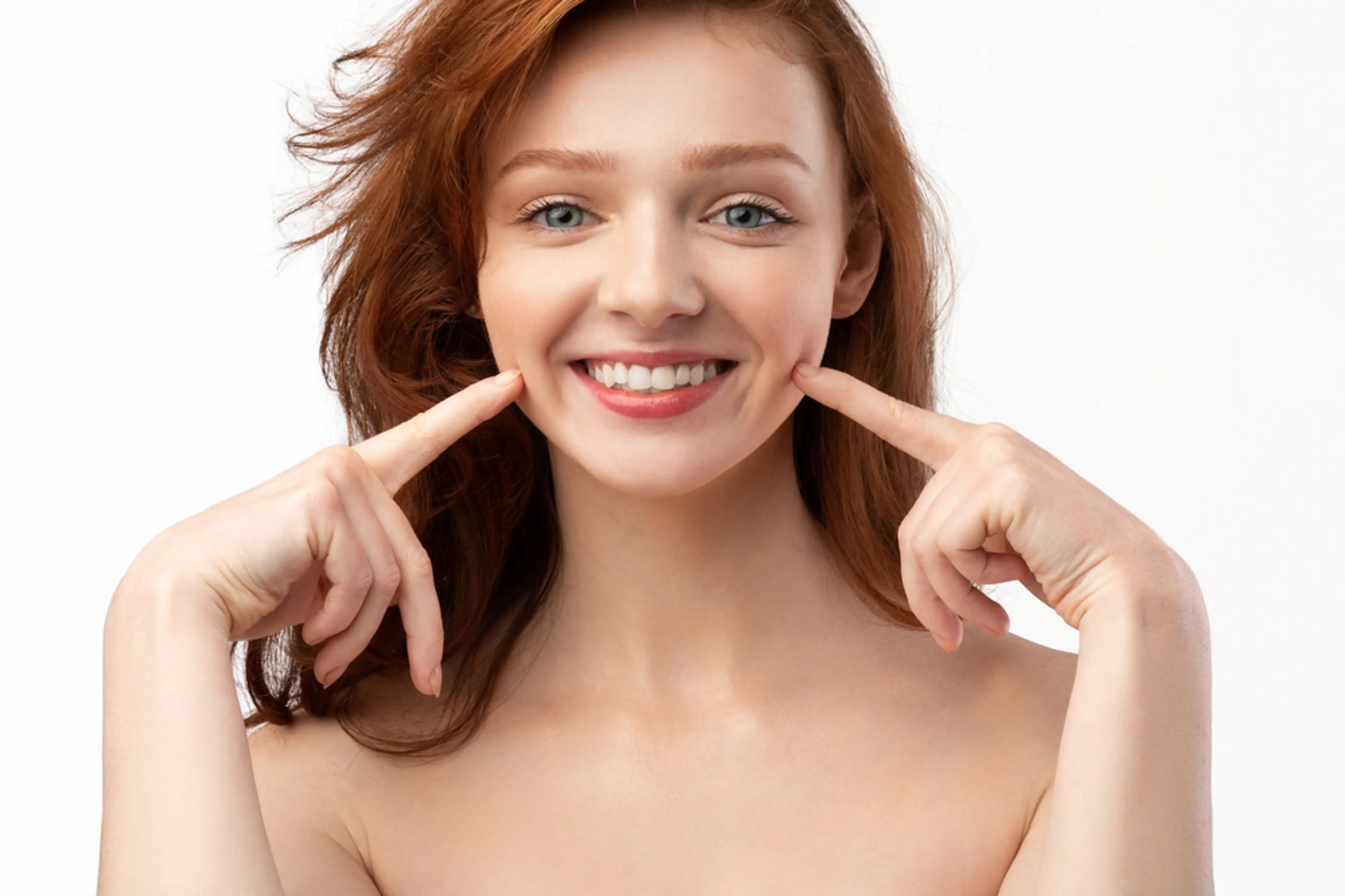 Smiling woman pointing to natural looking cheek dimples illustrating results of dimple creation surgery